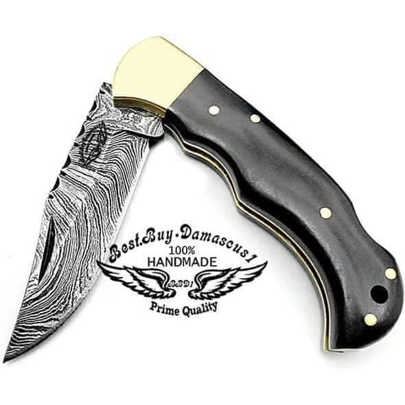 Damascus folding knife with black buffalo horn handle and brass bolster open on a white background — cover image for the knife gift for men guide