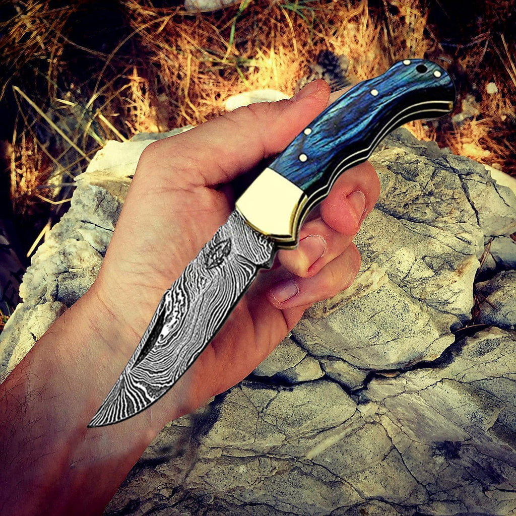 Handmade blue wood Damascus pocket knife held in hand, open