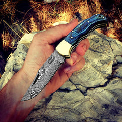 Handmade blue wood Damascus pocket knife held in hand, open